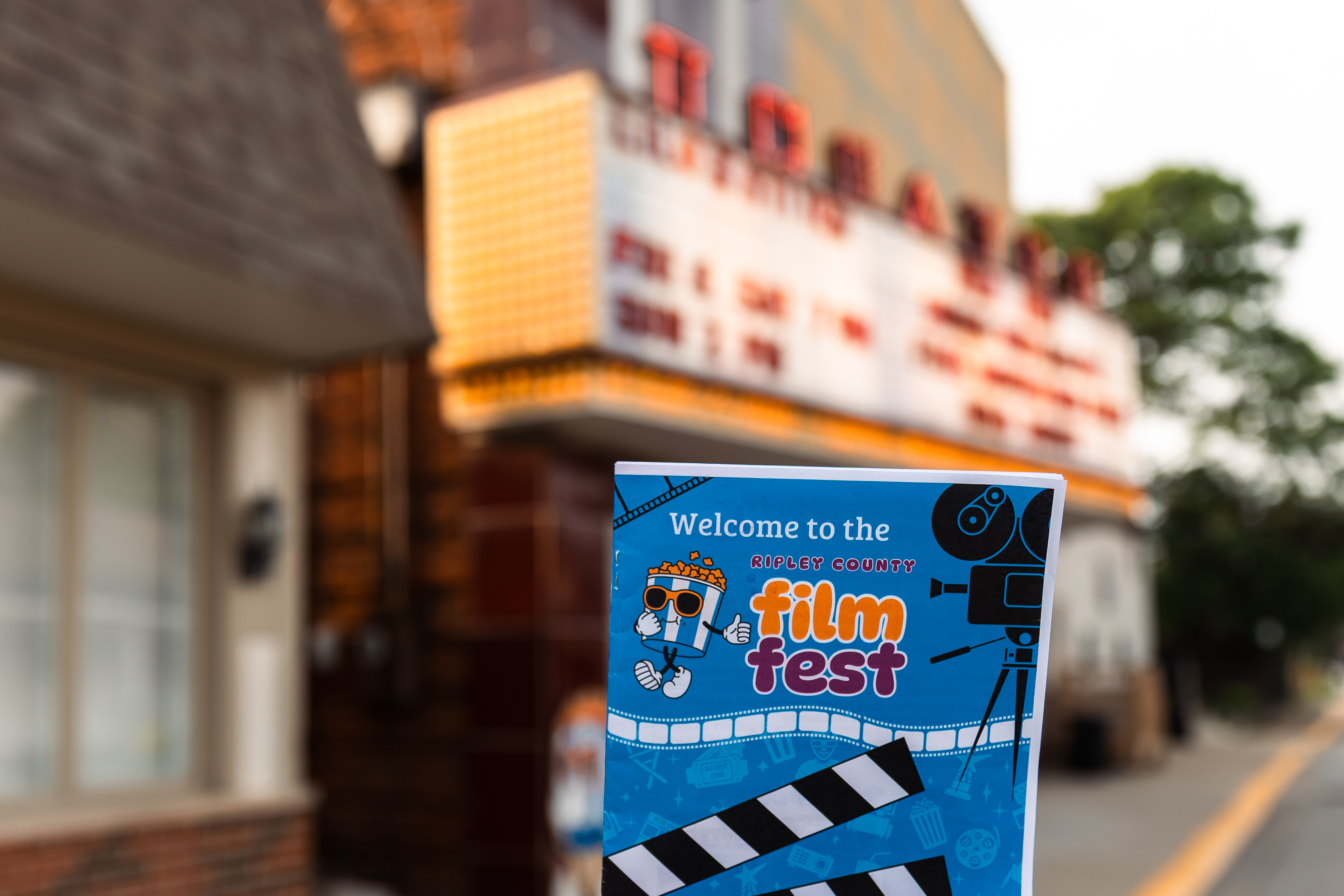 A Ripley County Film Fest program booklet held in front of the Gibson Theatre marquee in Batesville, Indiana