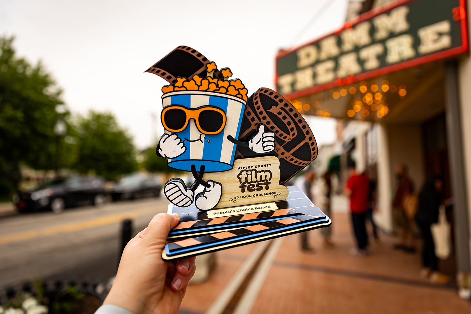 The Ripley County Film Fest People's Choice Award trophy held in front of the Damm Theatre marquee in Osgood, Indiana